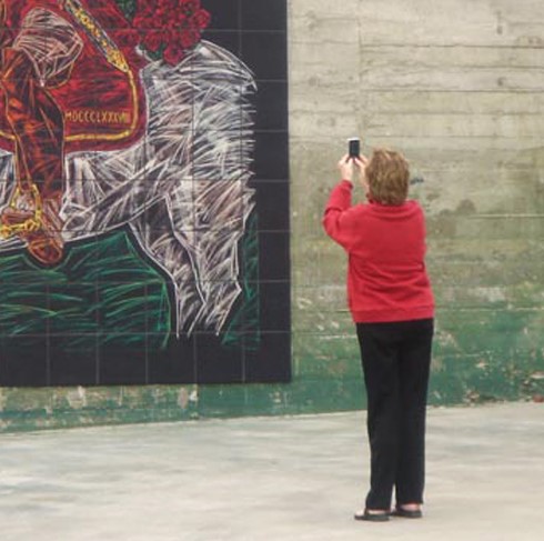 A USC fan takes a photo of the USC Traveler Mural at the Los Angeles Memorial Coliseum