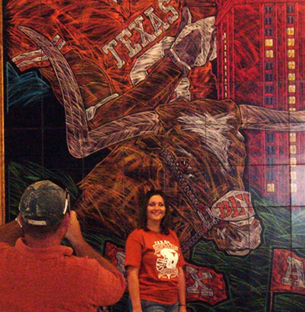 Texas Longhorn fans taking photogrpahs in front of the University of Texas Mural