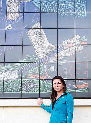 Simona Halep posing by her Championship Mural and the original canvas acrylic painting